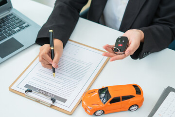 Sale agent handed over the rental car key to the customer who signed the contract and the terms of the agreement on the document, Car rental service and Insurance car concept.