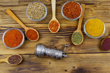 Set of different aromatic spices and spice mill on wooden table. Top view