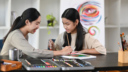 Fototapeta premium Asian girl having fun painting with teacher in art class.