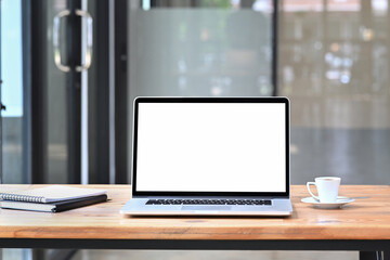 Computer laptop, coffee cup and books on wooden table.