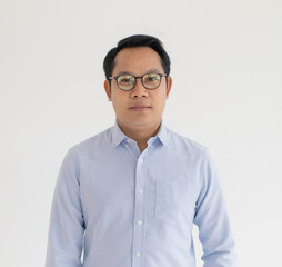 Portrat close up studio shot of Asian happy middle aged chubby plump male model wearing optical eyeglassess with blue casual shirt standing smiling look at camera in front or white wall background