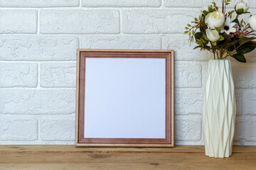 Picture frame mockup with white brick wall background and flower white vase. Mockup for design template.