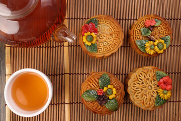 Colorful flower decorated mooncake cut slice half layer Chinese mid autumn festival on bamboo food mat glass teapot white ceramic teacup