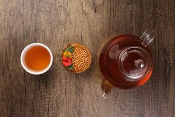 Colorful flower decorated mooncake cut slice half layer Chinese mid autumn festival on glass teapot white ceramic teacup over rustic wood border