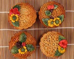 Colourful flower decorated mooncake Chinese mid autumn festival on bamboo food mat background