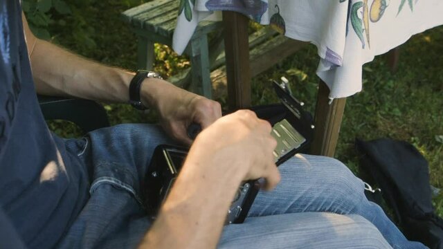 Caucasian man putting a film roll inside an old retro medium format camera.