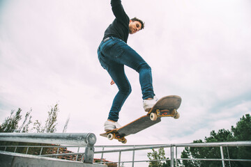 Young caucasian male skateboarder in the air jumping off a rail. Copy space. © Daniel