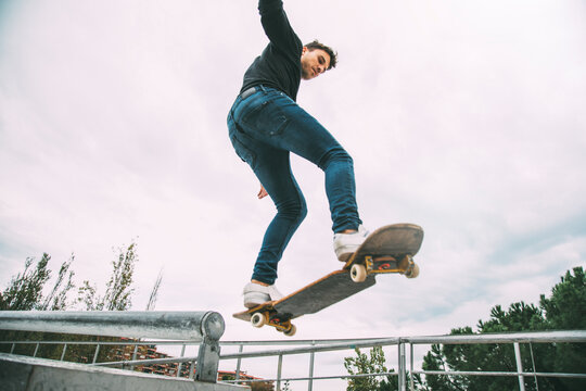 Young caucasian male skateboarder in the air jumping off a rail. Copy space.