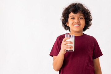 A HAPPY BOY POSING IN FRONT OF CAMERA WHILE HOLDING A GLASS OF MILK