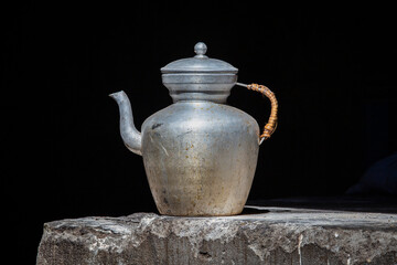 Old handmade tibetan kettle on black background . India, Ladakh