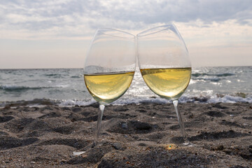 Romantic glass of white wine, on the sea beach. Wine tasting and relaxation at the resort