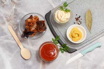 Grilled pork in a bowl with sauces and greens.