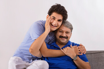 Indian father and son loving each other while sitting on sofa
