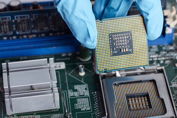 Blue glove holding CPU chip  with circuit board background