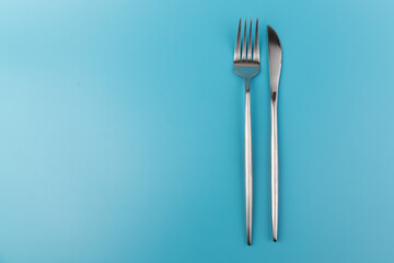 A fork and knife on blue background. Flat lay Dishes for breakfast, lunch or dinner.