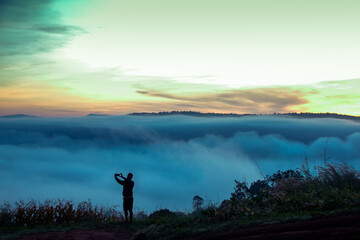 silhouette of man taking photo in clouds morning on top  mountain