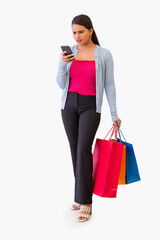 Indian young girl watching smartphone while holding shopping bags in her hand