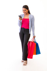 Indian young girl watching smartphone while holding shopping bags in her hand