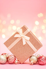 Gift box and Christmas ornaments on pink festive background.Vertical photo