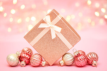 Gift box and Christmas ornaments on pink festive background