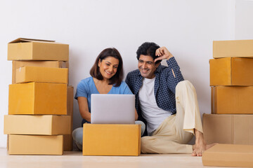 Indian middle age couple together watching laptop unpacked after moving to new room