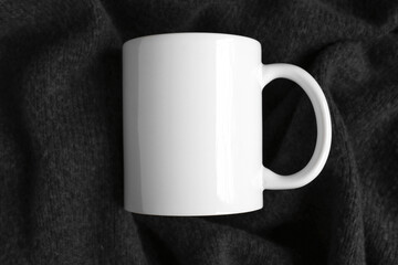White mug on a black textile background top view. Mockup cup for adding design and advertising, template with copy space.