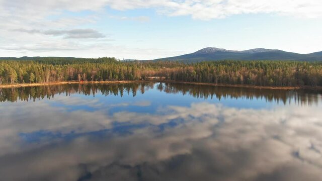 Swedish Lake Mirroring Cloudy Sky Near Alpine Forest Lakefront.