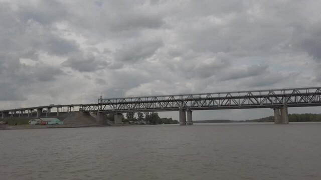 Steadicam shot from bow of sailing boat on the river with traffic bridge straight ahead when weather is partly cloudy