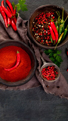 Red chili or chilli cayenne pepper and peppercorns on dark background.