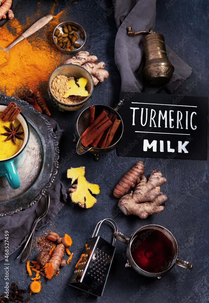 Wall mural healthy turmeric golden milk on dark background.