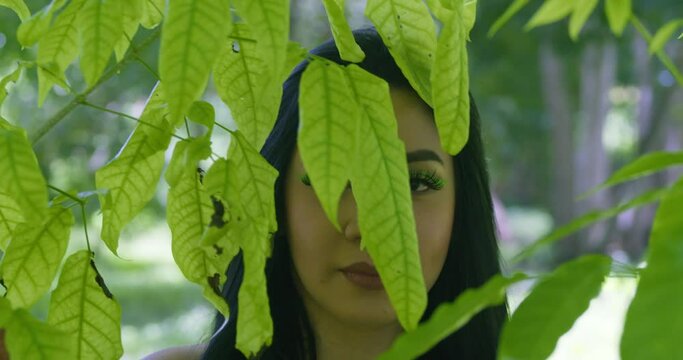 Latina facial model walks in the leaves of a large tree at a tropical park