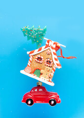 New Year's card, poster, creative. A red car is carrying sweets, a New Year gingerbread house and a candy in the form of a Christmas tree on a blue background.