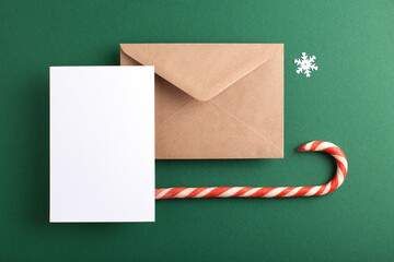 Blank card, kraft envelope and Christmas decoration on green background. Holiday and Season's...