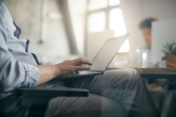 Close-up of businessman works on computer during meeting in office.