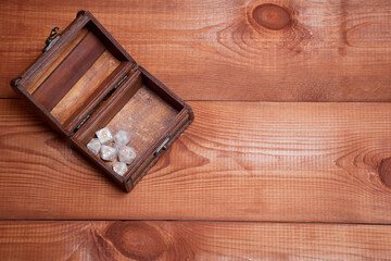 Set of role playing white dices lie in storage box on gaming table made of wood, top view: concept for role-playing games with place for text