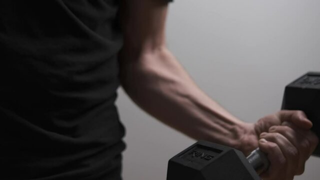4K footage showing an unrecognizable person workout indoor, man lifting up a weight exercise. Physical and muscle weight training for body building workout dramatic light