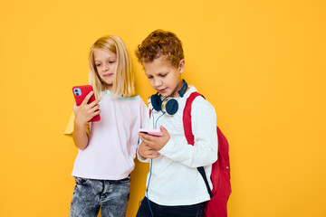 Two kids boy and girl with school backpacks phone entertainment communication Studio education concept