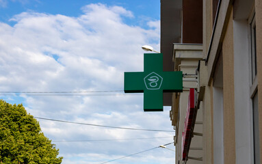 The green cross logo. Pharmacy, sign on the street on the facade of the building against the sky