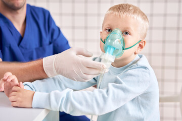 A pediatrician diagnoses lung disease and provides treatment. Breathe the medicine through a nebulizer inhaler.. Portrait of adorable little boy visiting doctor.