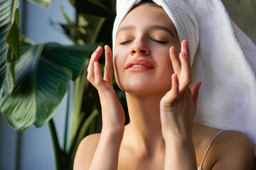 Close-up shot of a beautiful young woman applying face cream.