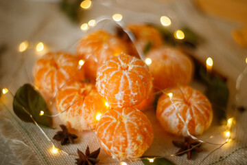Fresh Clementines or Tangerines in the Basket on Brown Wooden Table with Xmas Lights and Tree Branches