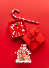 Gingerbread house, red clock, gift, lollipop, candy on a red background.