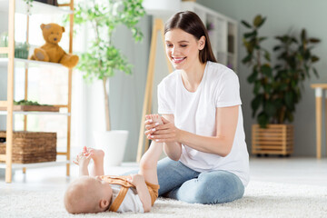 Photo of positive charming redhead mother hold small infant child leg shiny smile wear casual outfit home indoors