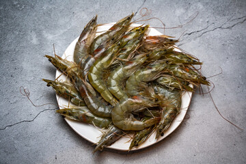 Raw shrimps lie on a white plate.