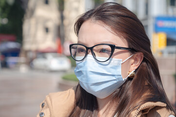 Close up portrait virus outbreak air pollution pretty Chinese young woman wearing facial protection mask on street. Prevention of respiratory diseases during covid pandemic. Healthcare between people.