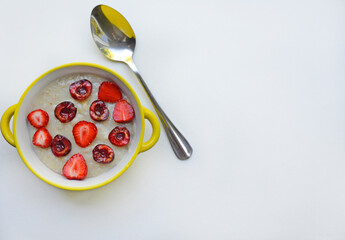 A plate of oatmeal with cut ripe juicy strawberries on a white table. there is a spoon next to the plate. healthy and healthy breakfast concept