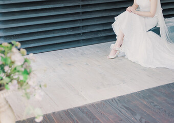 Fototapeta na wymiar A bride sitting in a wedding dress in front of the stairs.