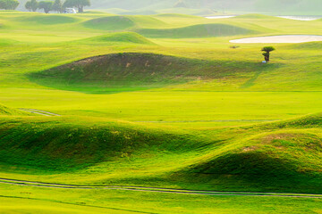 The beautiful green view of green grass and sand banker on golf course with cloudy sky background.