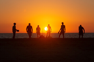 Un grupo de amigos juegan y se divierten al atardecer en la playa de Los Lances, Tarifa, Cádiz,...