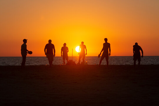 Un grupo de amigos juegan y se divierten al atardecer en la playa de Los Lances, Tarifa, Cádiz, Andalucía, España